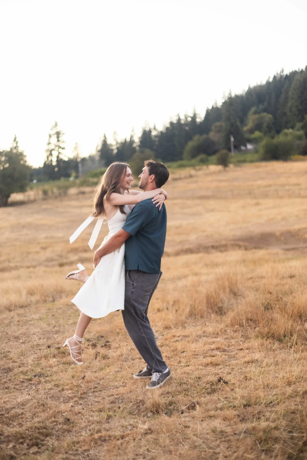 Groom lifting bride in the golden field at sunset