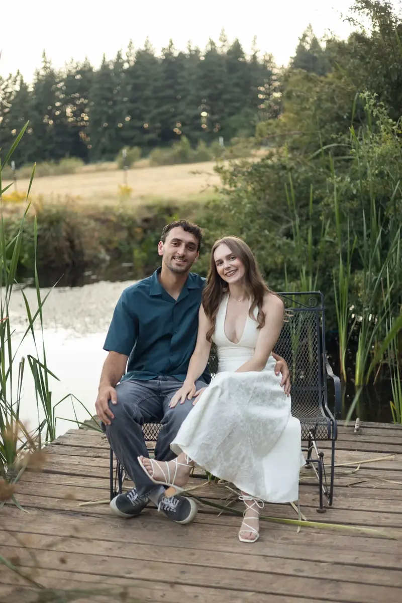 Couple seated on the pond dock bench with cattails and pasture behind