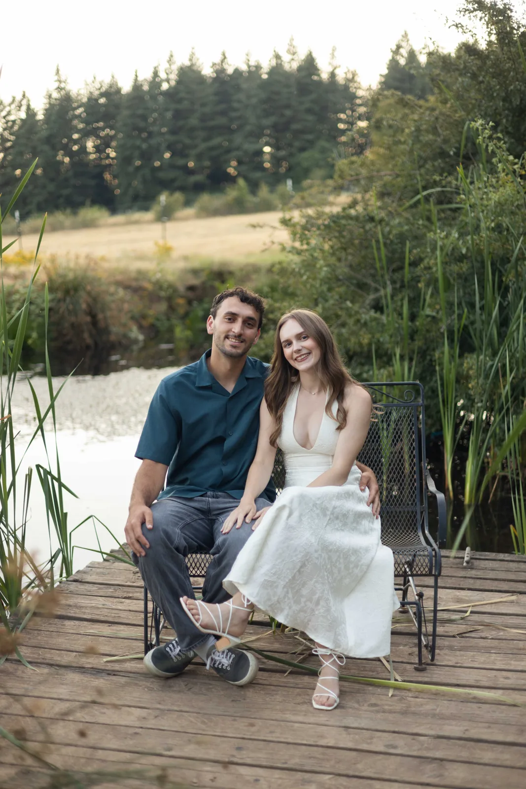 Couple seated on the pond dock bench with cattails and pasture behind