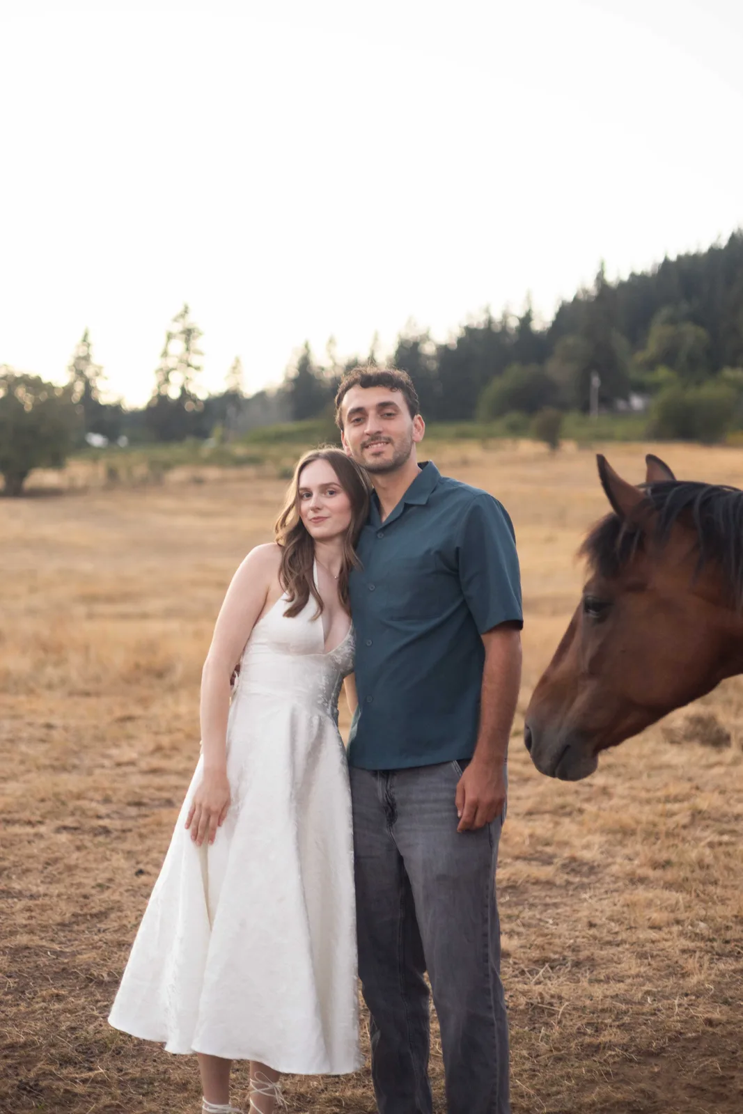 Couple portrait in the pasture with a curious horse